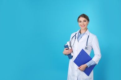 Photo of Young medical student with clipboard and books on color background. Space for text