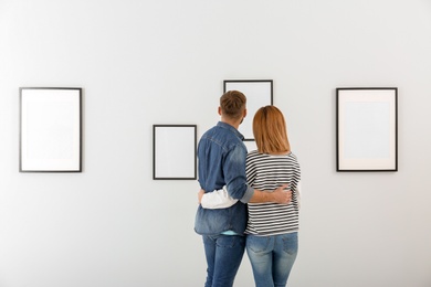 Photo of Couple viewing exposition in modern art gallery