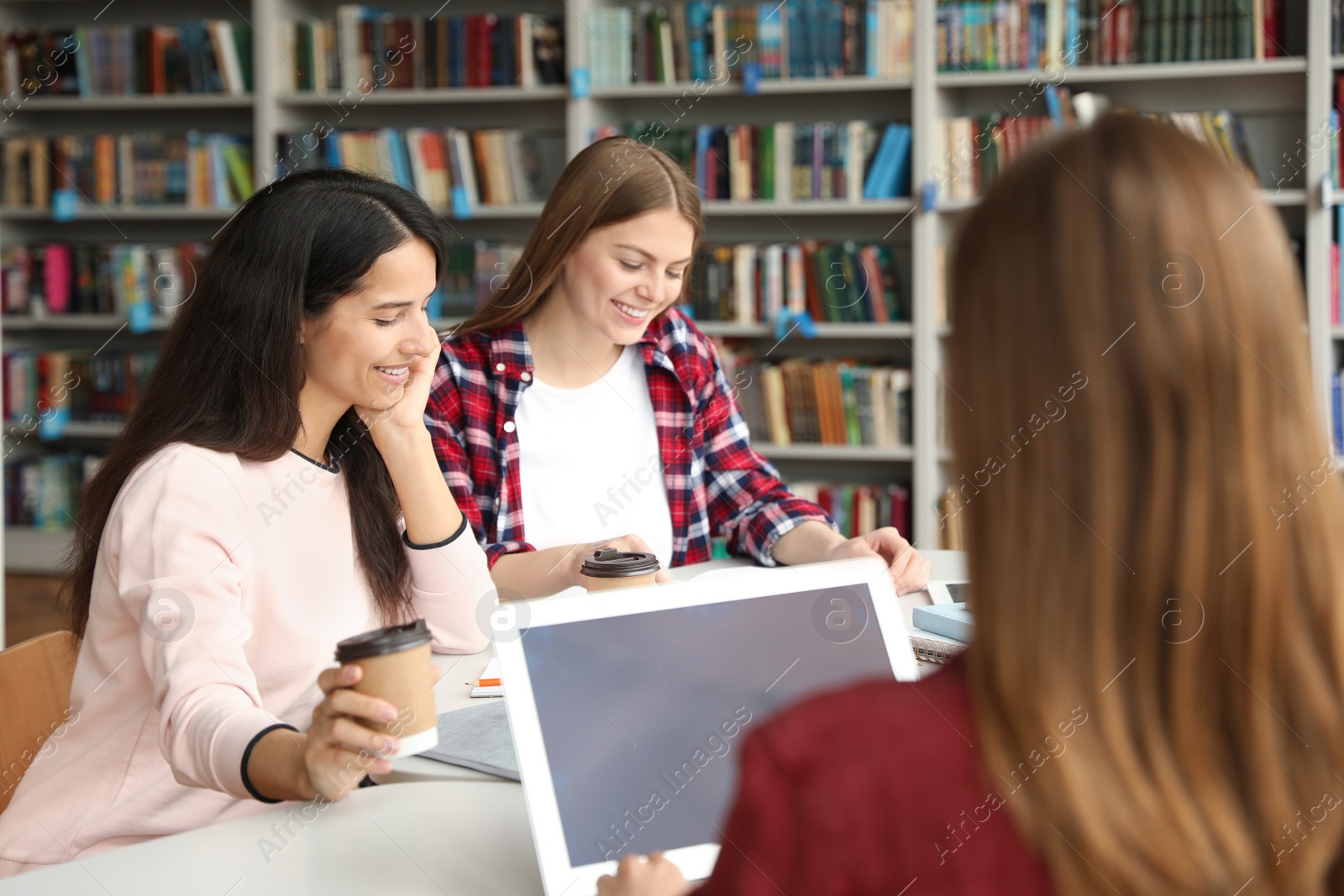 Photo of Young people discussing group project at table in library