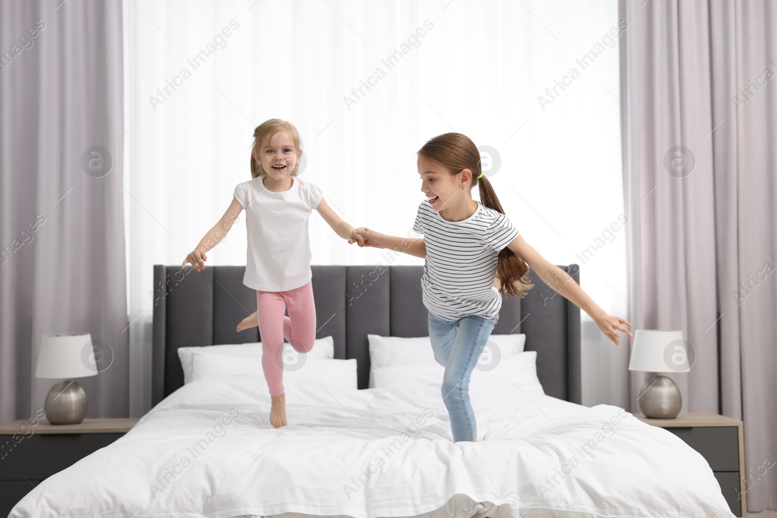 Photo of Cute little sisters having fun together on bed at home