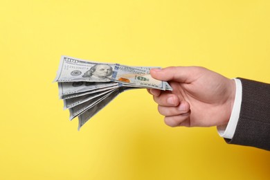 Photo of Man holding money on yellow background, closeup. Currency exchange