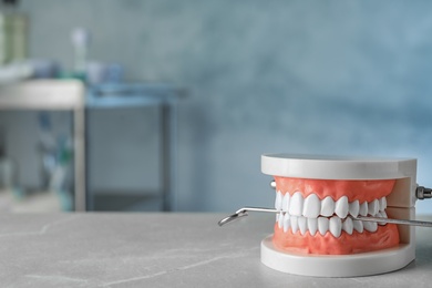 Educational model of oral cavity and dentist mirror on table indoors. Space for text