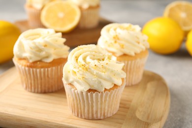 Tasty cupcakes with cream, zest and lemons on light grey table, closeup