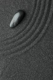 Photo of Zen garden stone on black sand with pattern, top view