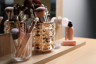 Photo of Set of professional brushes and makeup products near mirror on wooden table, space for text