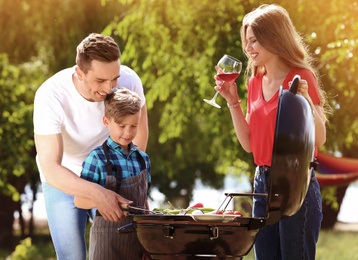 Image of Happy family having barbecue with modern grill outdoors 
