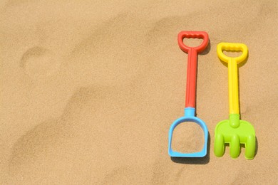 Plastic shovel and rake on sand, space for text. Beach toys