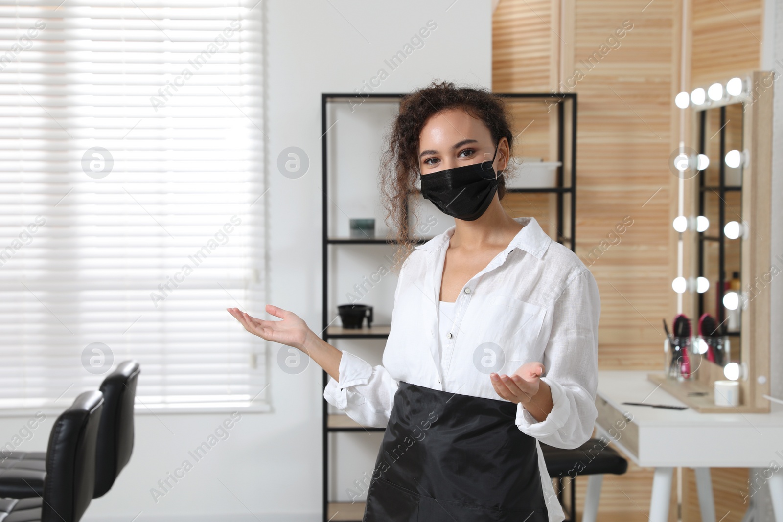 Photo of Professional stylist with protective mask in salon. Hairdressing services during Coronavirus quarantine