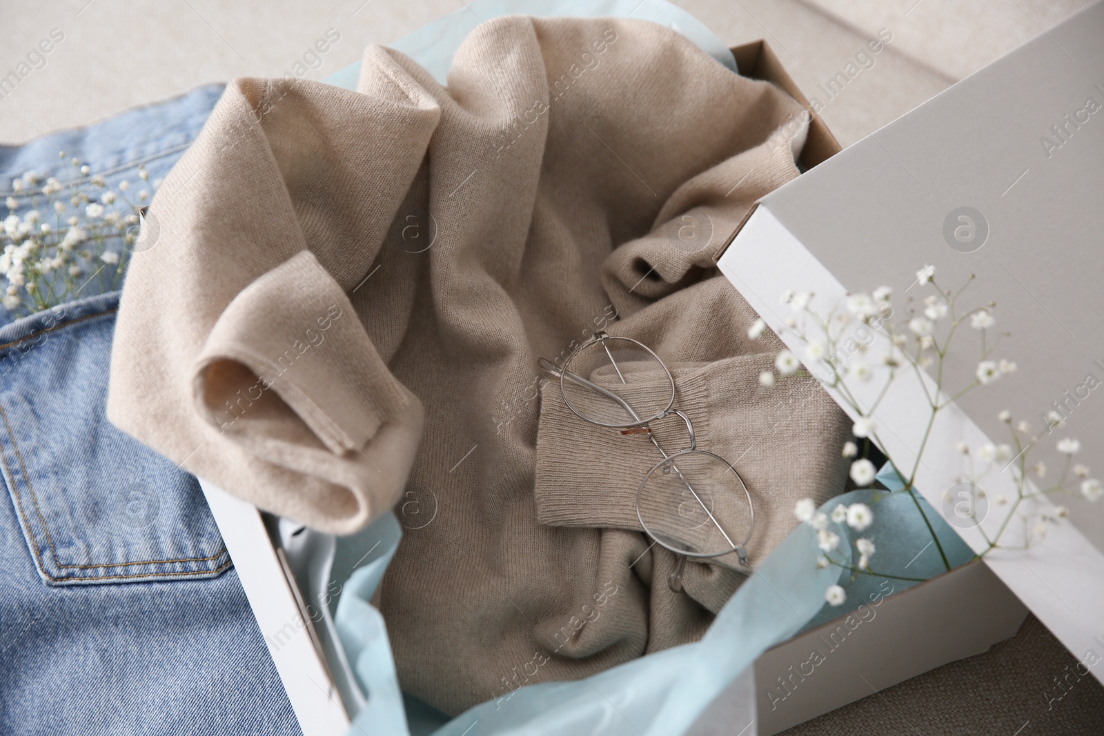 Photo of Soft cashmere sweater in box on sofa, closeup