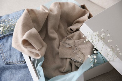 Photo of Soft cashmere sweater in box on sofa, closeup