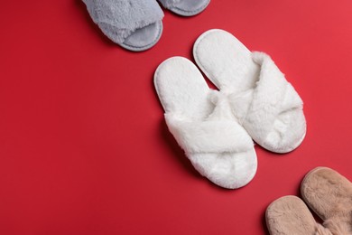 Photo of Different soft fluffy slippers on red background, flat lay. Space for text