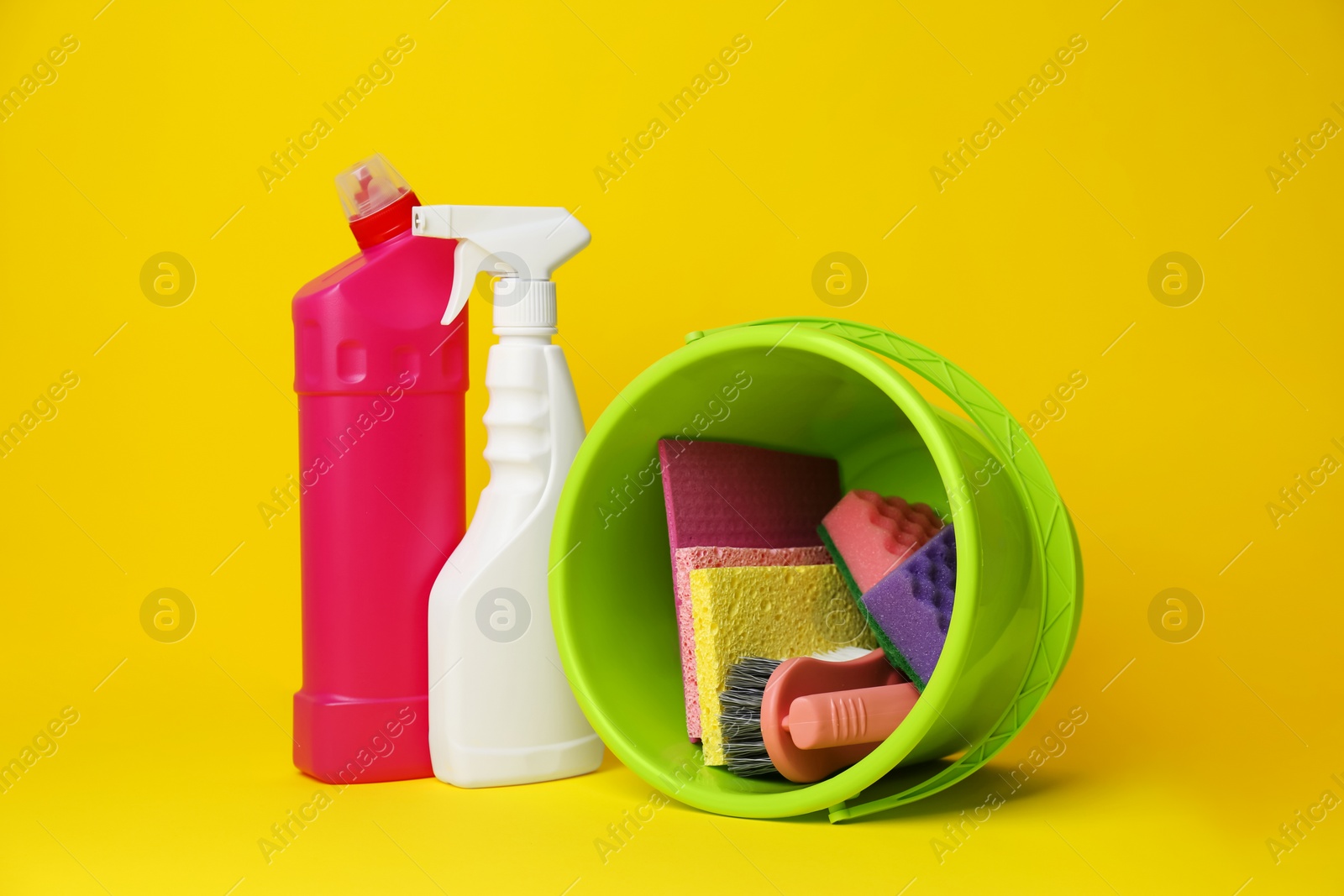 Photo of Green bucket, cleaning supplies and tools on yellow background