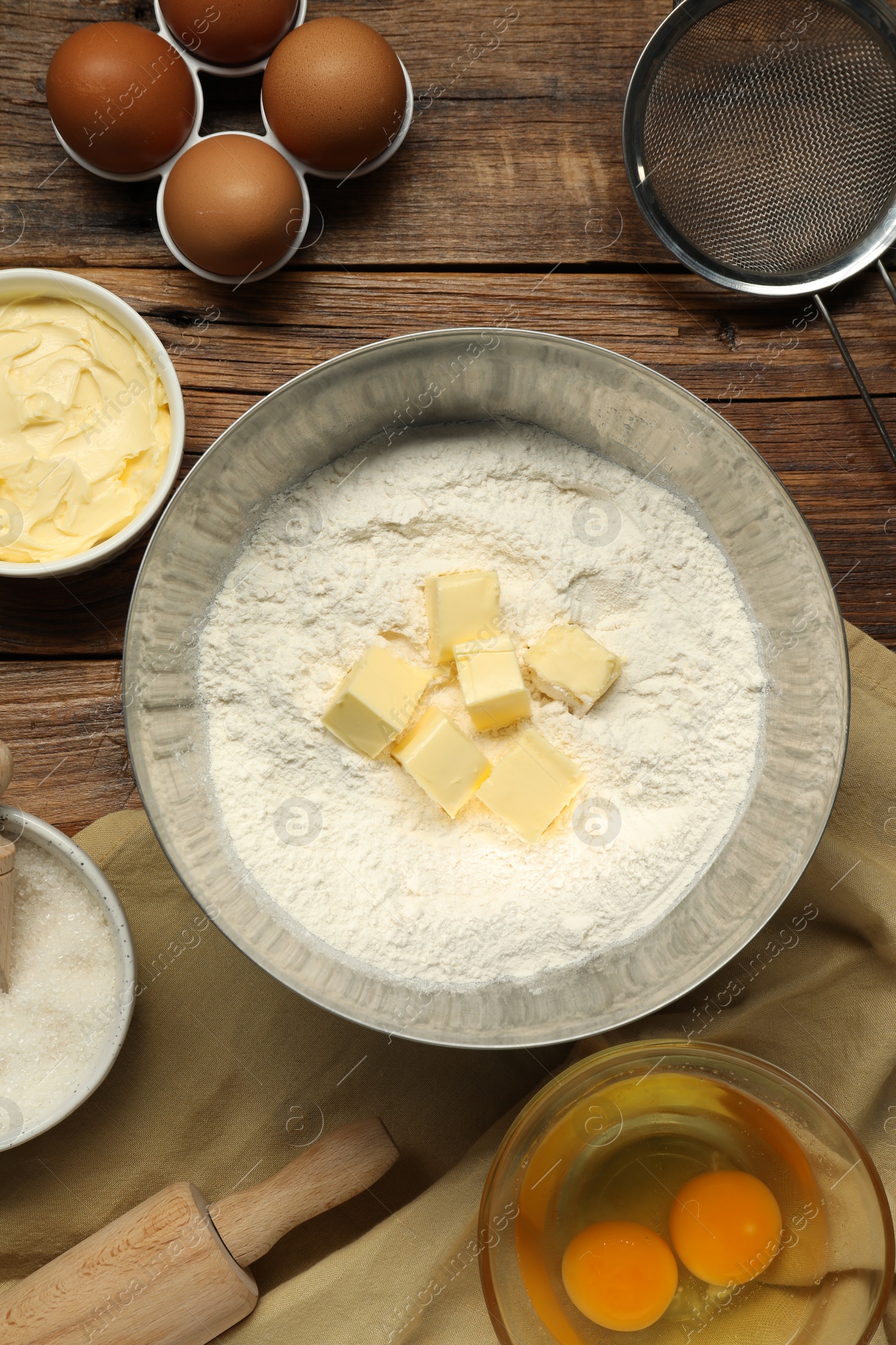 Photo of Flat lay composition with fresh butter and flour in bowl among other products on wooden table