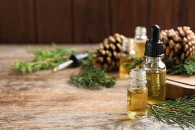 Photo of Composition with bottles of conifer essential oil on wooden table. Space for text