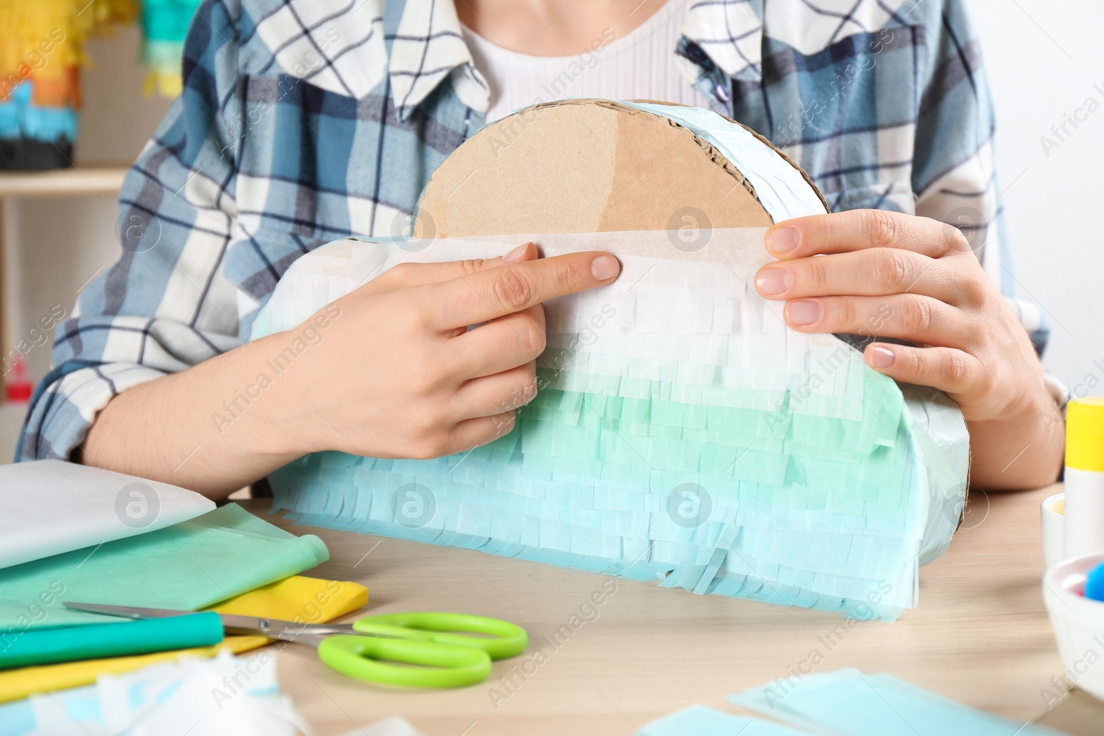 Photo of Woman decorating cardboard cloud at table, closeup. Pinata diy