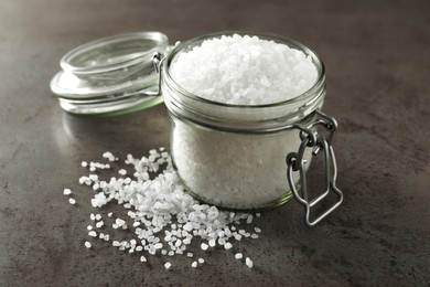 Photo of Glass jar of natural sea salt on grey table