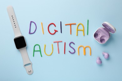 Photo of Phrase Digital Autism made of colorful plasticine, smartwatch and earphones on light blue background, flat lay. Addictive behavior