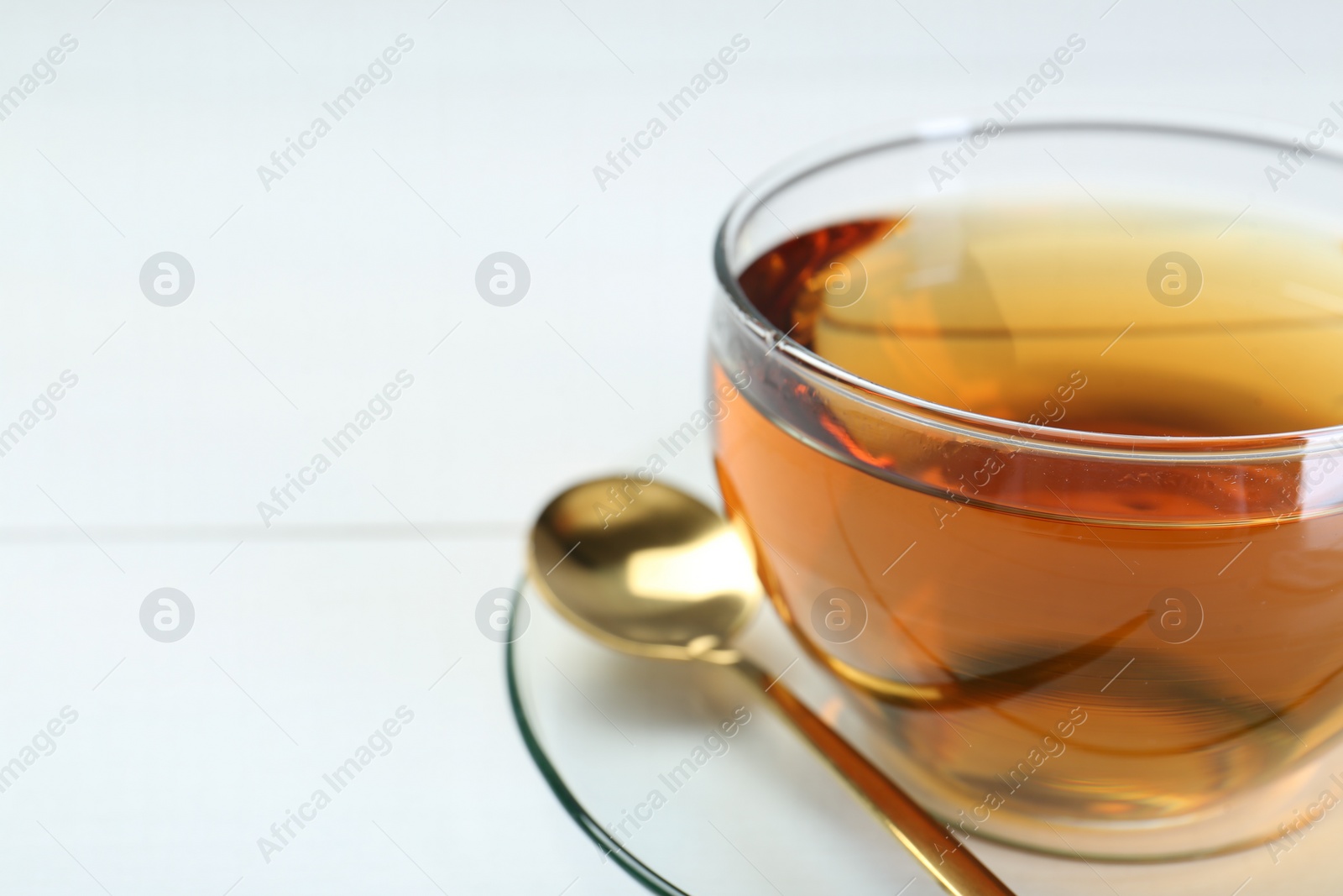 Photo of Glass cup of tea on white table, closeup. Space for text