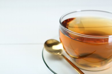 Glass cup of tea on white table, closeup. Space for text