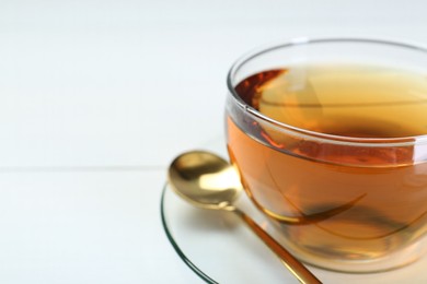 Photo of Glass cup of tea on white table, closeup. Space for text