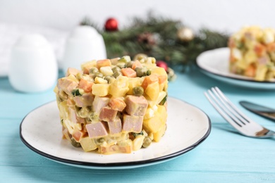 Photo of Traditional russian salad Olivier served on turquoise wooden table, closeup