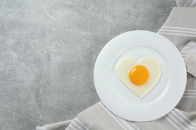 Romantic breakfast with heart shaped fried egg on light grey table, top view. Space for text