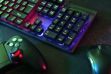 Photo of Modern RGB keyboard, mouse and video game controller on grey table, closeup