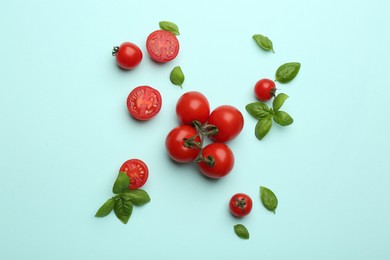 Photo of Fresh cherry tomatoes and basil leaves on light blue background, flat lay