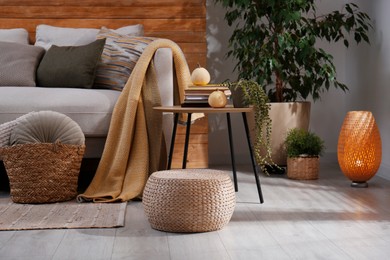 Photo of Stylish living room interior with comfortable sofa and wicker pouf