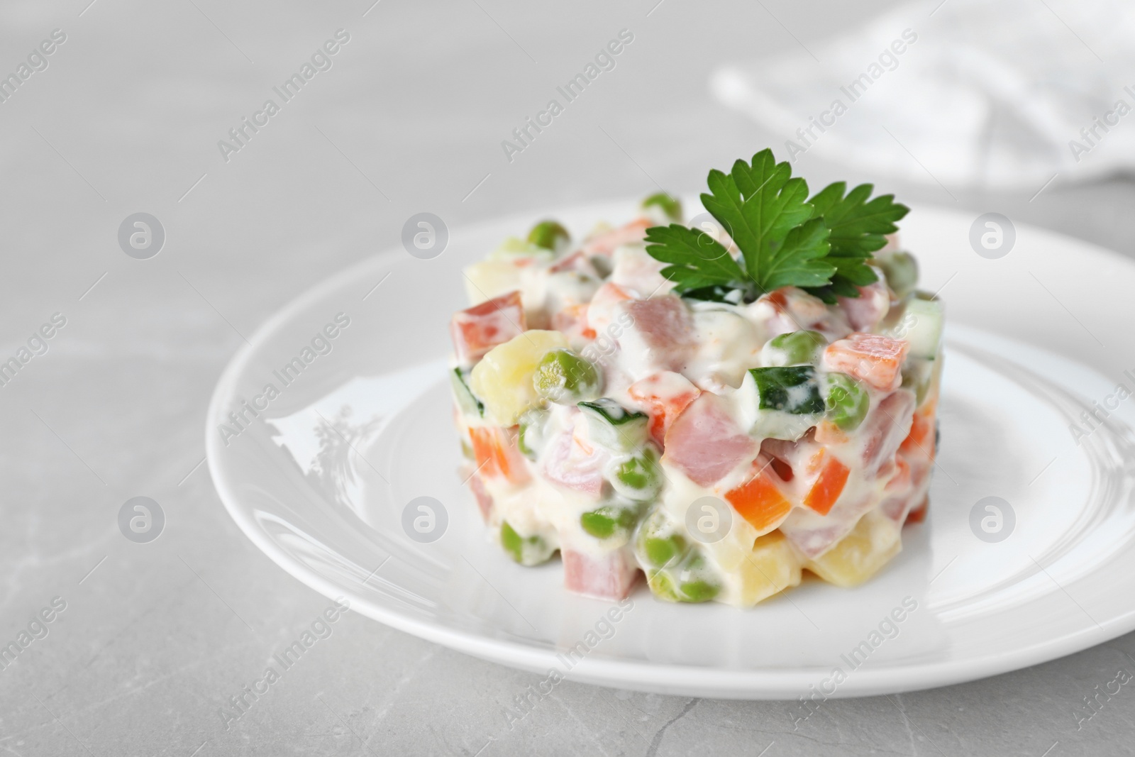 Photo of Delicious salad Olivier in plate on light table, closeup