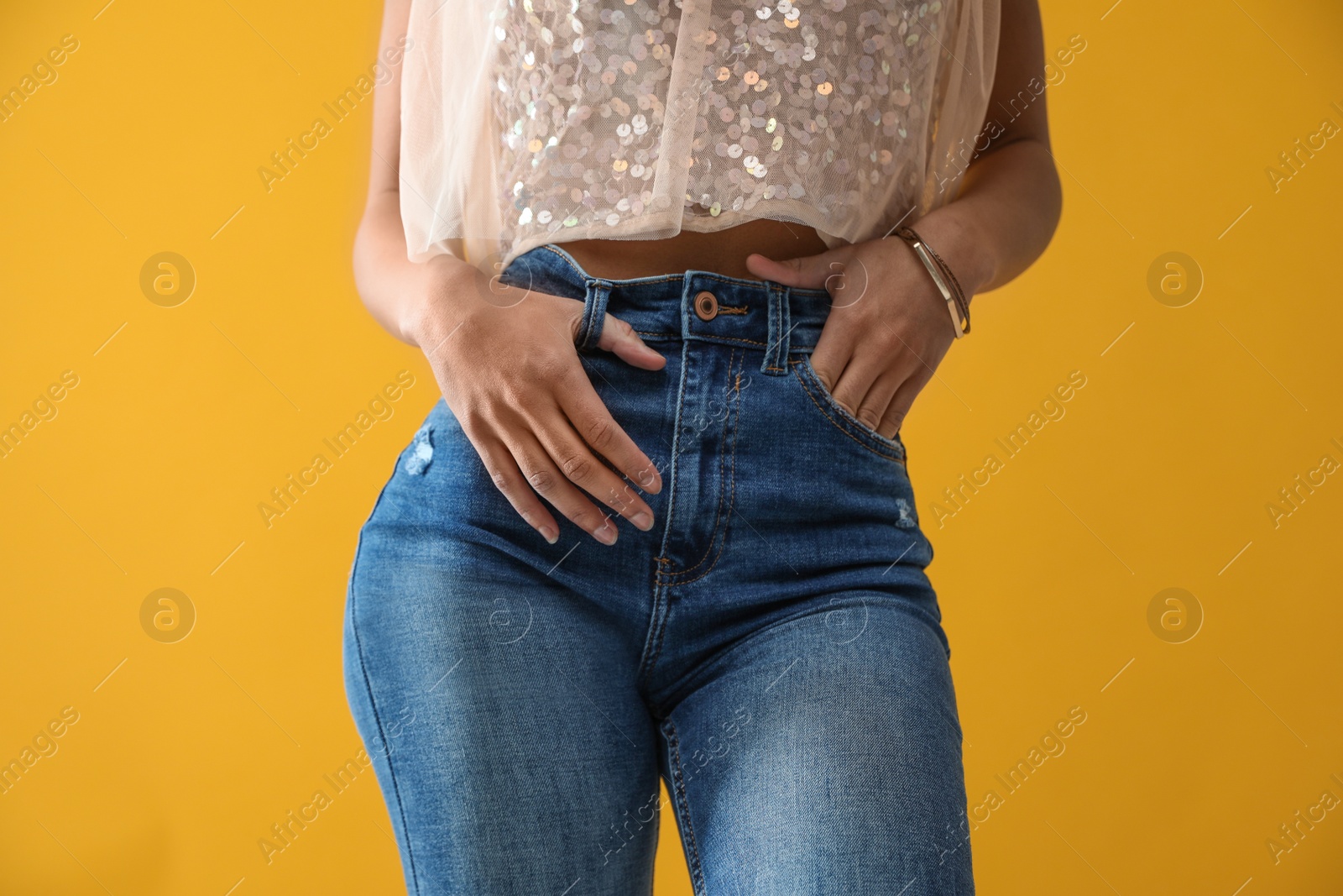 Photo of Woman wearing jeans on yellow background, closeup