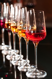 Row of glasses with different wines on table against blurred background