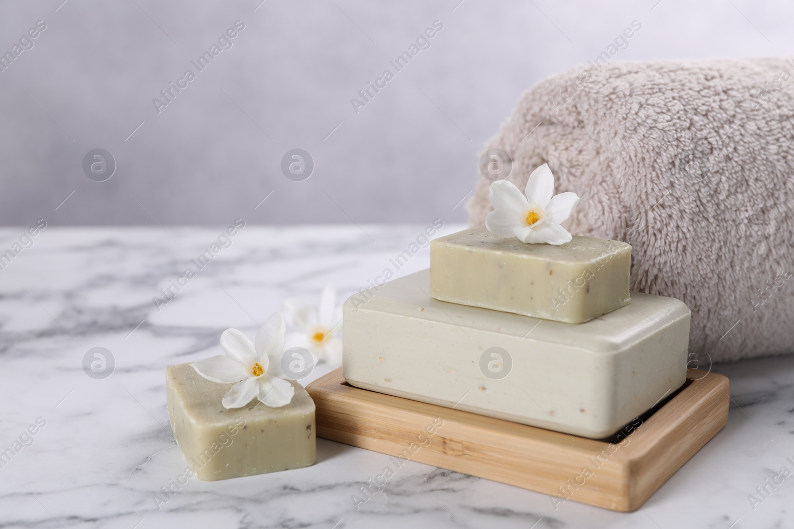 Photo of Spa composition with soap, flowers and towel on white marble table