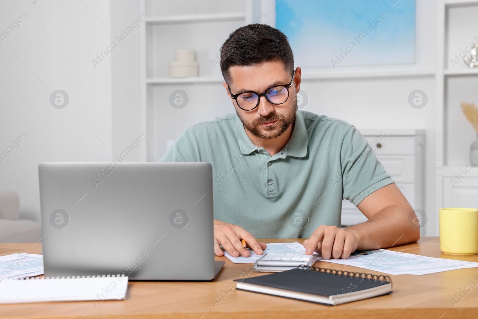 Photo of Man calculating taxes at table in room