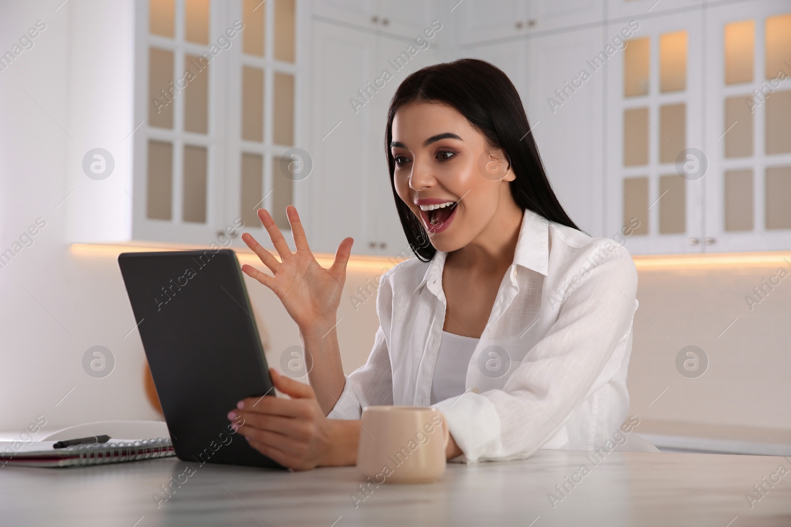 Photo of Emotional woman participating in online auction using tablet at home