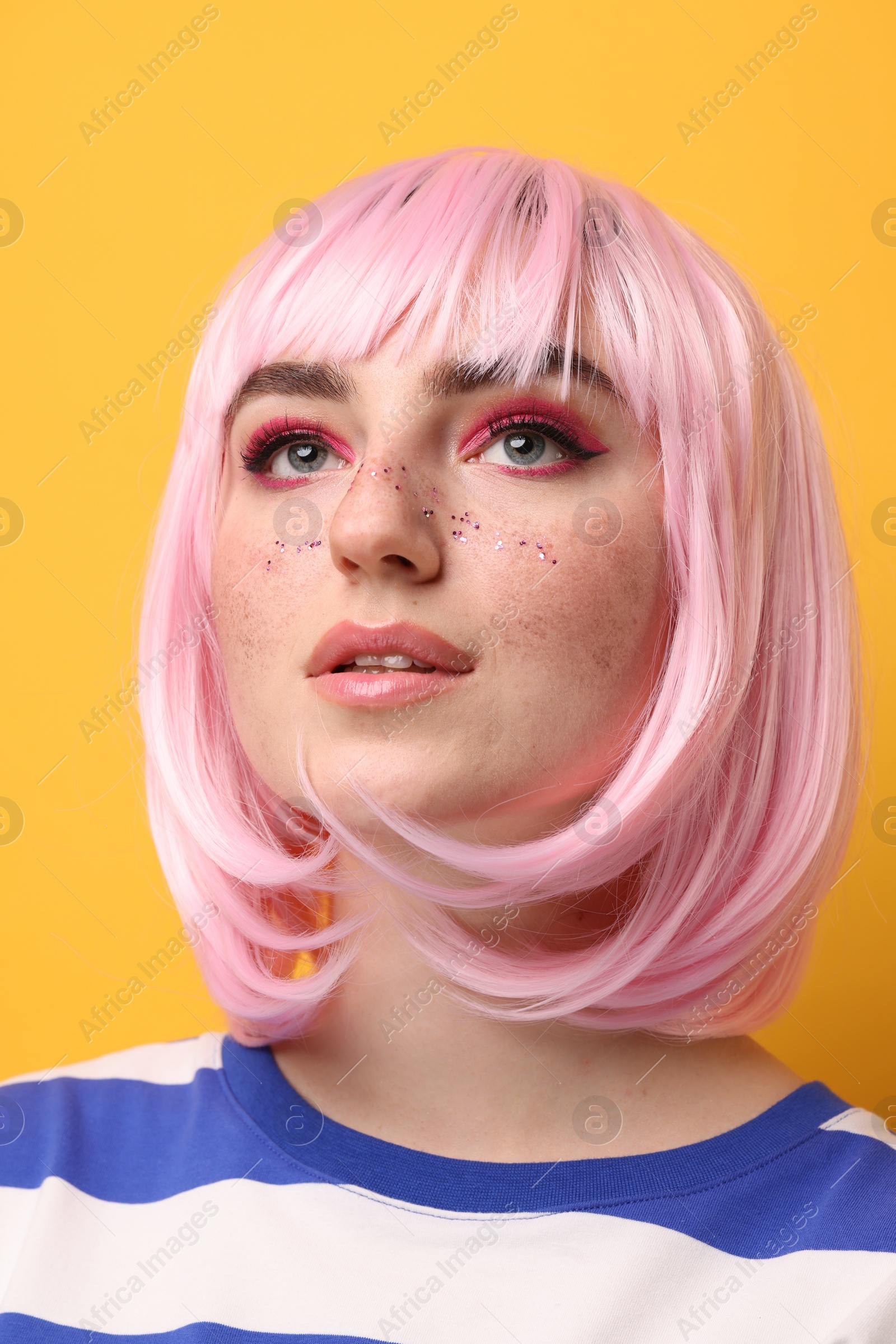 Photo of Beautiful woman with bright makeup and glitter freckles on yellow background