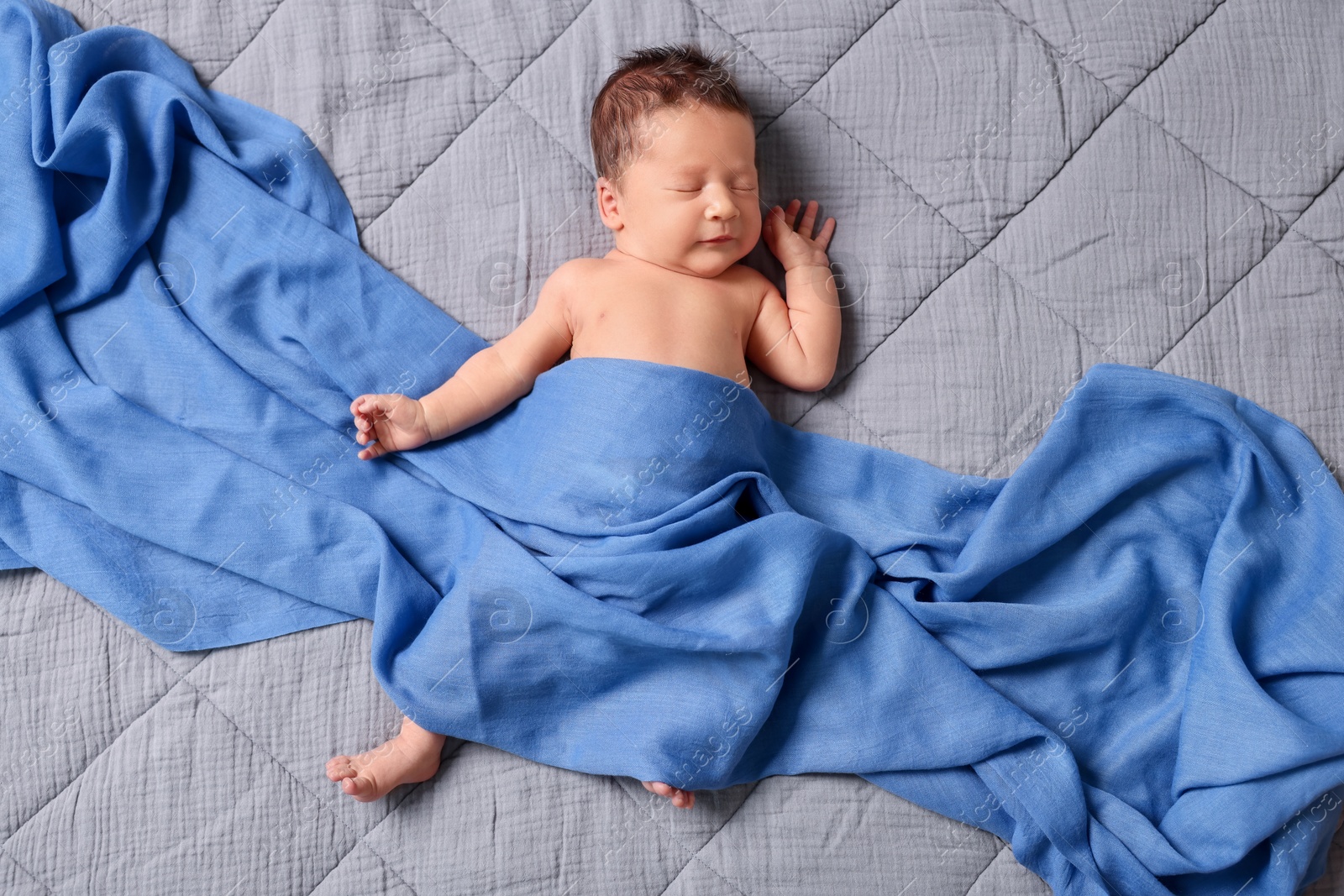 Photo of Adorable newborn baby sleeping under blue blanket on bed, top view