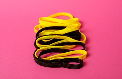 Photo of Yellow and black shoe laces on pink background