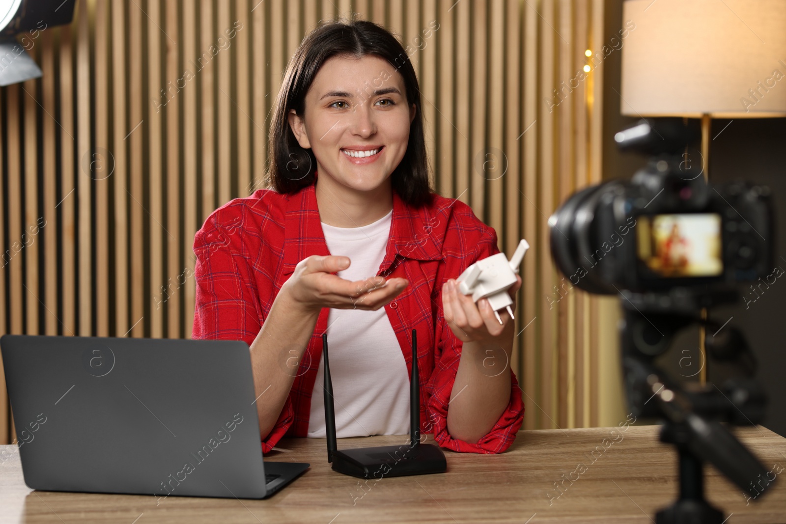 Photo of Smiling technology blogger recording video review about WI-FI extender at home