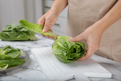 Photo of Woman with fresh ripe cos lettuce on table