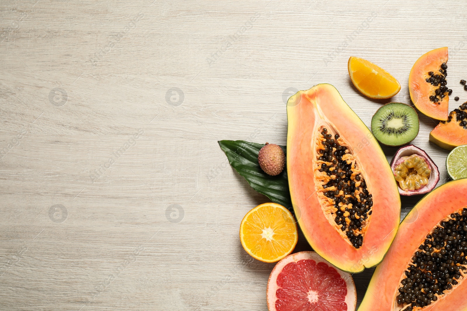 Photo of Fresh ripe papaya and other fruits on wooden table, flat lay. Space for text