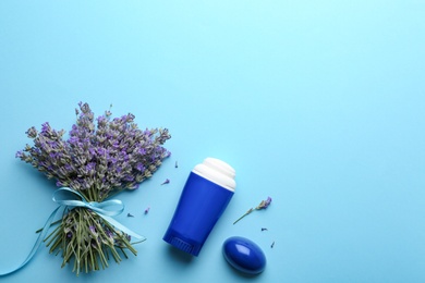 Female deodorant and lavender flowers on light blue background, flat lay