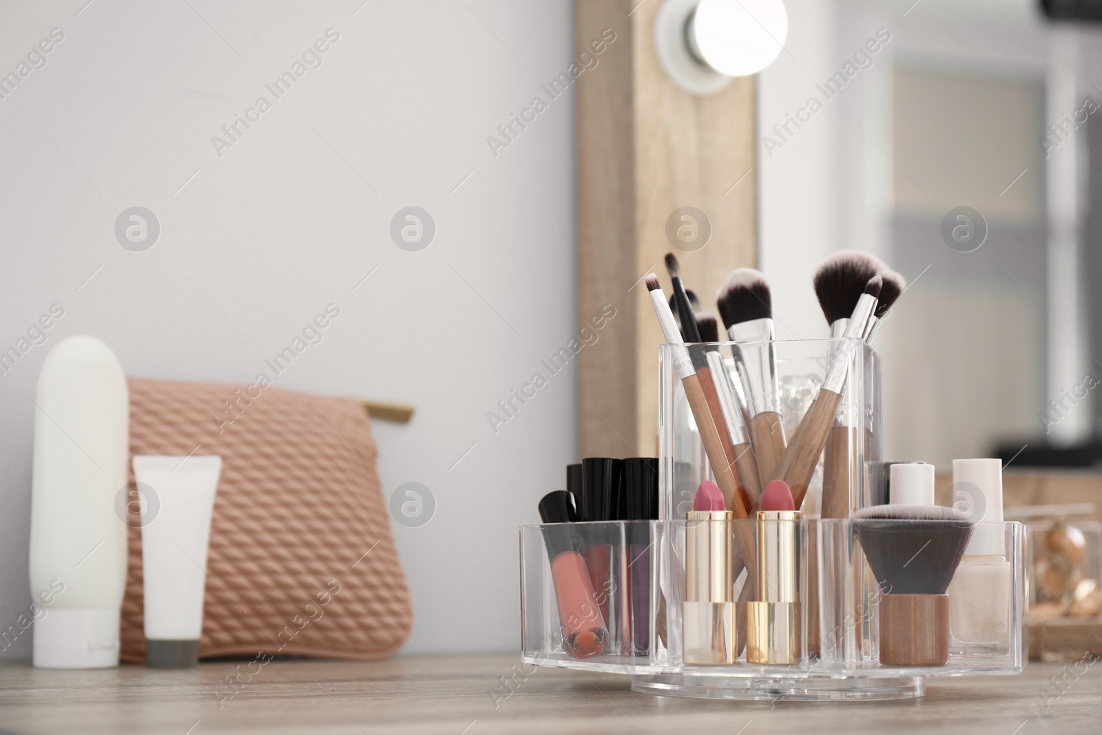 Photo of Organizer with cosmetic products for makeup on table near mirror