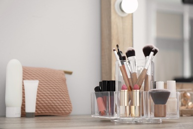 Photo of Organizer with cosmetic products for makeup on table near mirror