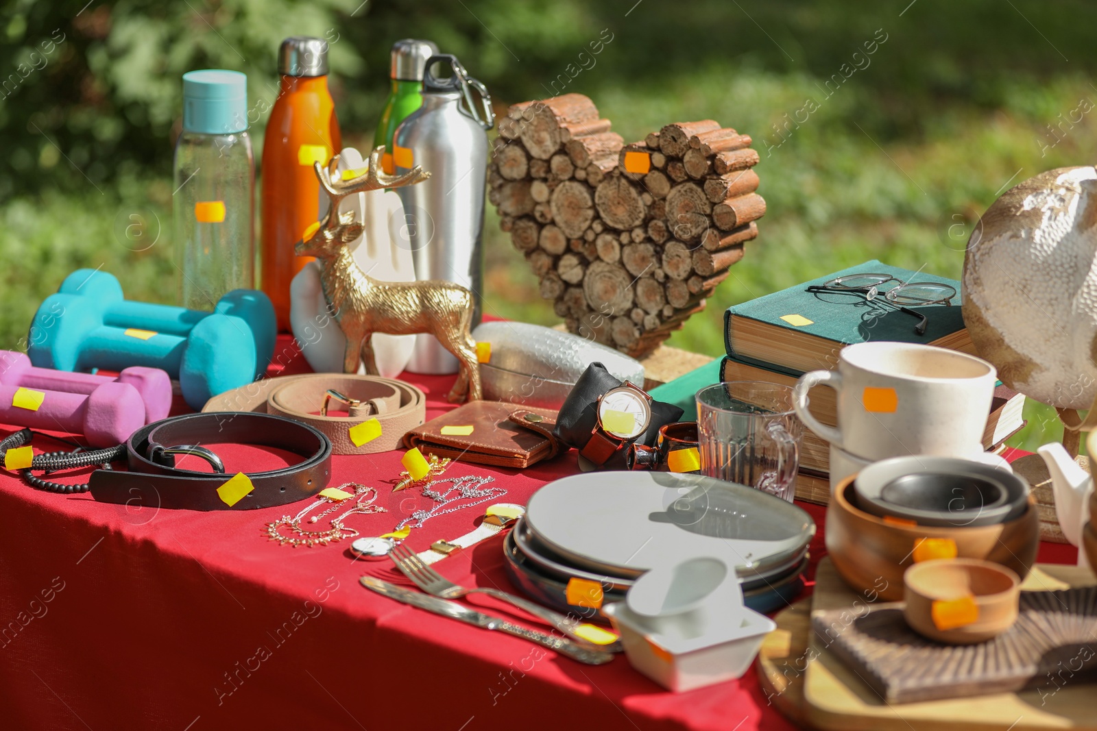 Photo of Many different items on table outdoors. Garage sale