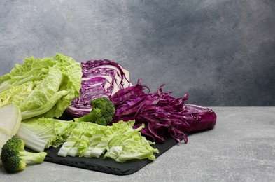 Photo of Different types of cut cabbage on light grey table, space for text