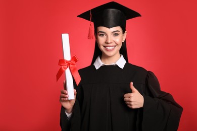 Photo of Happy student with graduation hat and diploma on red background