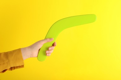 Photo of Woman holding boomerang on yellow background, closeup