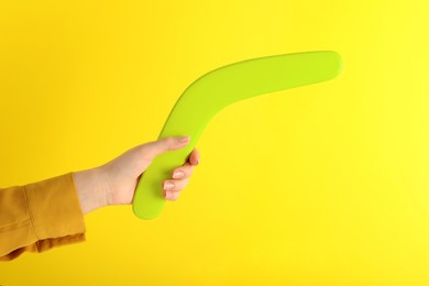 Woman holding boomerang on yellow background, closeup