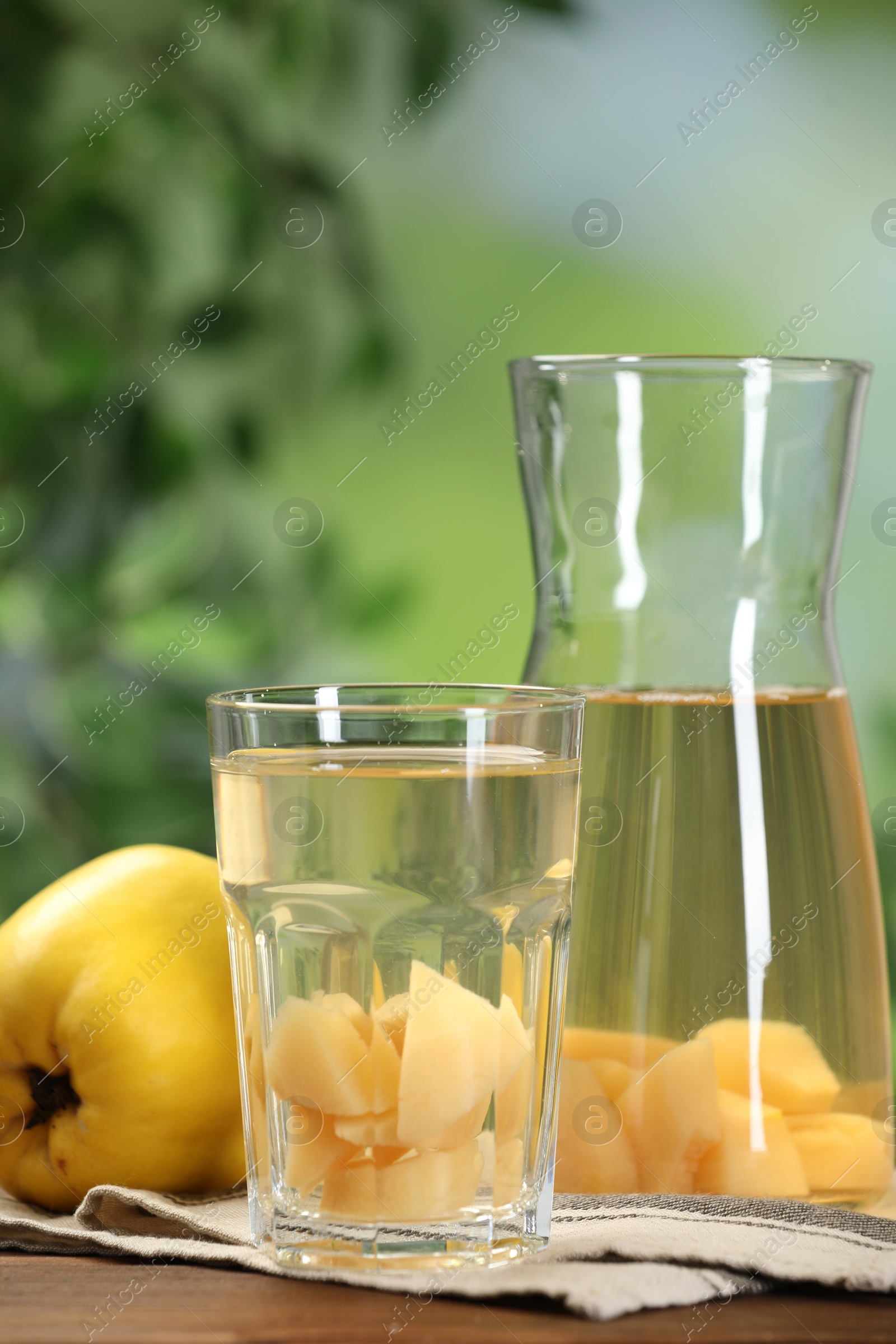 Photo of Delicious quince drink and fresh fruits on wooden table against blurred background